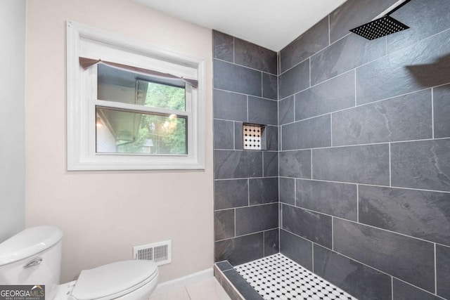 bathroom featuring tiled shower and toilet