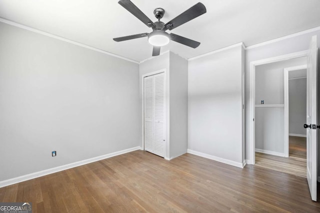 unfurnished bedroom with a closet, ceiling fan, crown molding, and hardwood / wood-style flooring