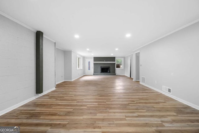 unfurnished living room featuring a large fireplace, crown molding, and light hardwood / wood-style flooring