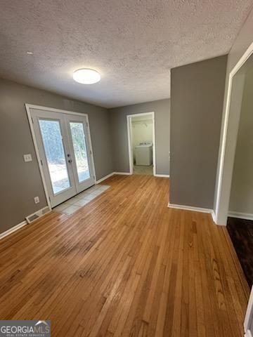 interior space featuring french doors, a textured ceiling, and light hardwood / wood-style flooring