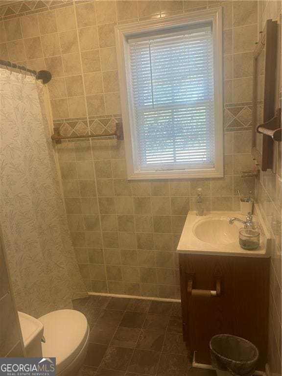 bathroom with walk in shower, vanity, tile walls, tile patterned flooring, and toilet