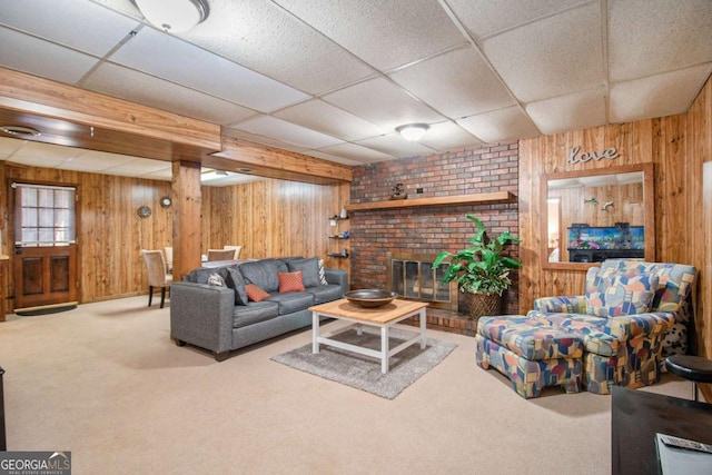 living room featuring a paneled ceiling, wood walls, carpet floors, and a fireplace