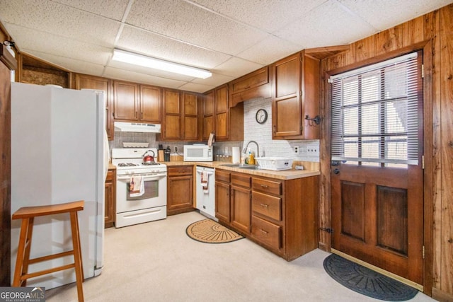 kitchen with a paneled ceiling, white appliances, sink, and tasteful backsplash