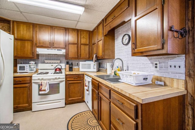 kitchen with decorative backsplash, white appliances, a drop ceiling, and sink