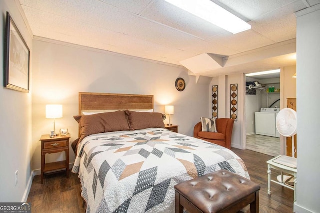 bedroom featuring a walk in closet, crown molding, dark hardwood / wood-style floors, washer / dryer, and a closet