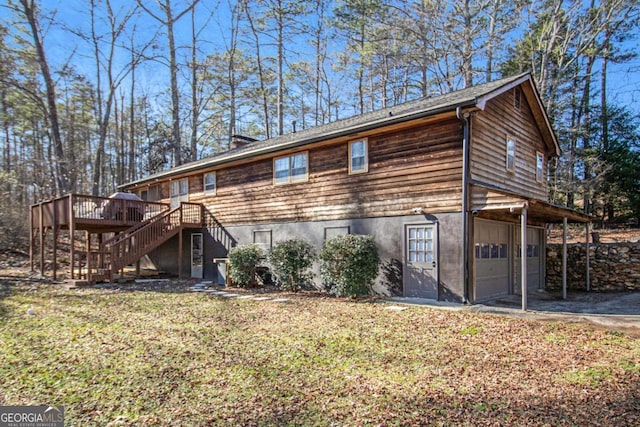 rear view of property with a garage and a deck