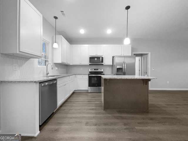 kitchen featuring stainless steel appliances, white cabinetry, a kitchen island, and sink