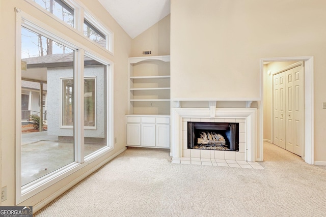 carpeted living room featuring high vaulted ceiling and a tile fireplace