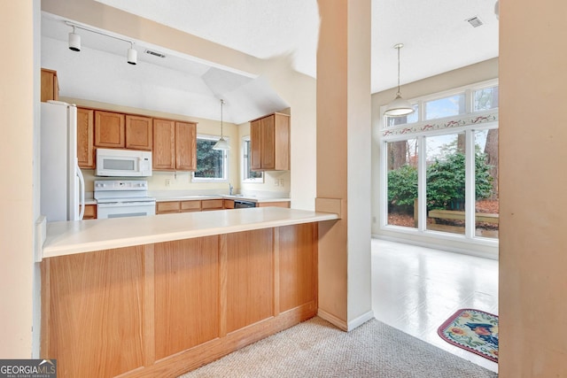 kitchen with plenty of natural light, decorative light fixtures, white appliances, and kitchen peninsula