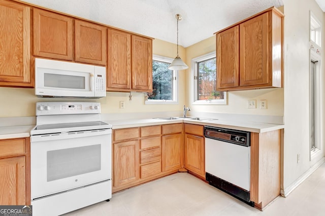 kitchen featuring pendant lighting, sink, white appliances, and a textured ceiling