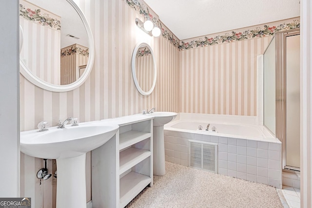 bathroom with tiled tub and a textured ceiling