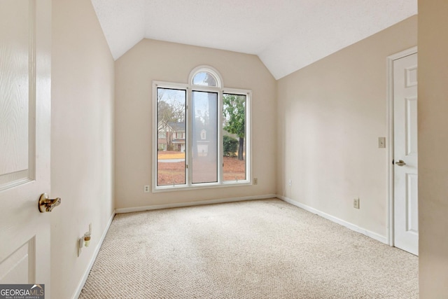 carpeted empty room featuring lofted ceiling