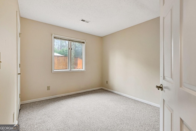 empty room featuring light colored carpet and a textured ceiling