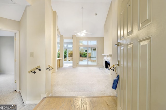 hallway with light carpet and high vaulted ceiling