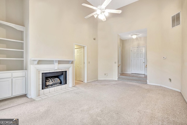 unfurnished living room featuring ceiling fan, light colored carpet, high vaulted ceiling, and a tile fireplace