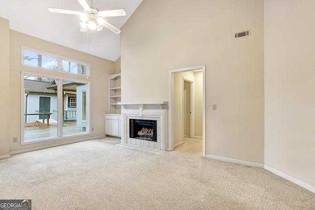 unfurnished living room featuring a tiled fireplace, light carpet, and high vaulted ceiling