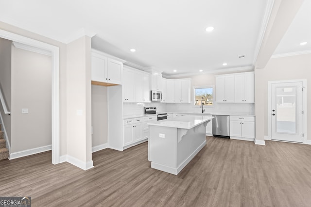 kitchen featuring white cabinets, a kitchen island, stainless steel appliances, backsplash, and light wood-type flooring