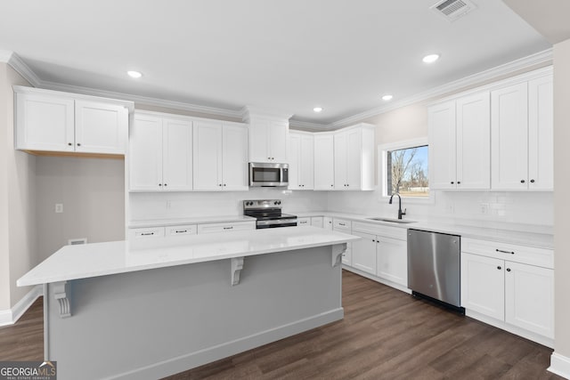 kitchen featuring appliances with stainless steel finishes, white cabinetry, a kitchen island, and sink