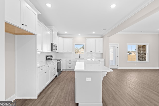 kitchen with decorative backsplash, white cabinetry, stainless steel appliances, and a kitchen island