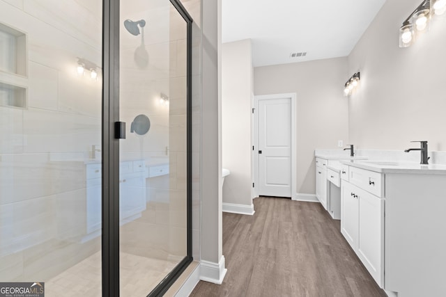 bathroom featuring hardwood / wood-style floors, walk in shower, and vanity