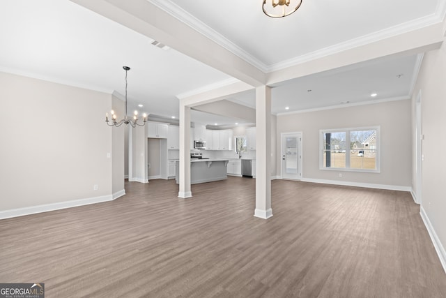 unfurnished living room with ornamental molding, sink, wood-type flooring, and a notable chandelier