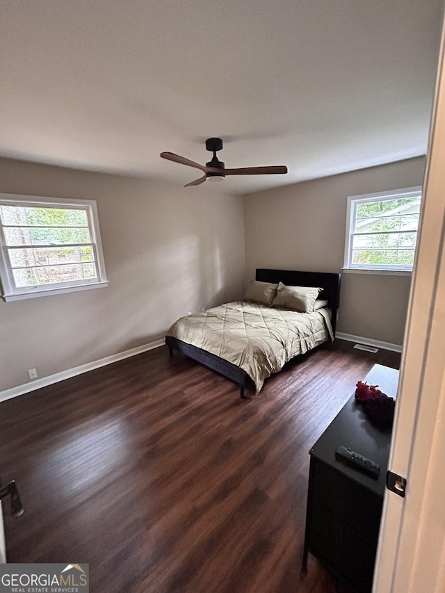 bedroom featuring ceiling fan, dark wood-type flooring, and multiple windows