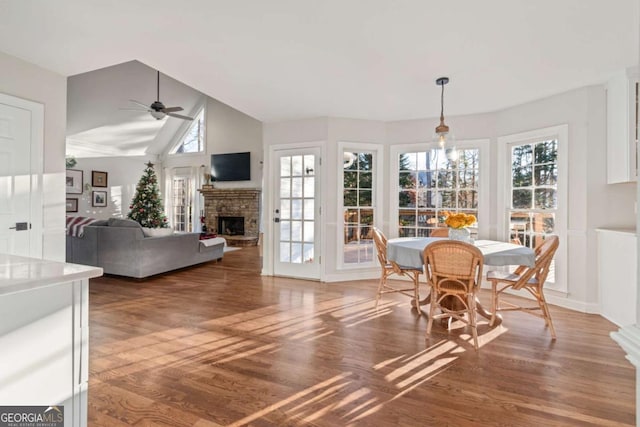 dining room featuring dark hardwood / wood-style floors, a brick fireplace, plenty of natural light, and ceiling fan