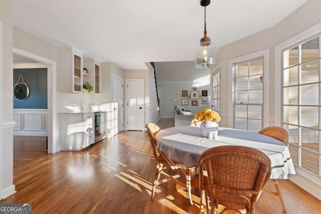 dining space with beverage cooler and hardwood / wood-style flooring