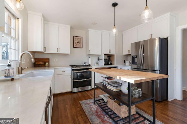 kitchen with wooden counters, stainless steel appliances, sink, pendant lighting, and white cabinets