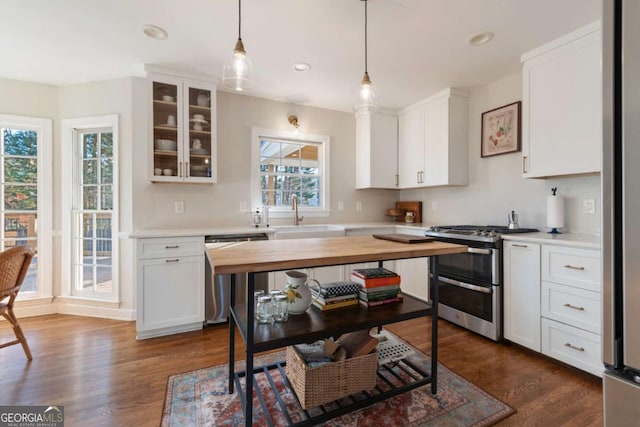 kitchen featuring sink, dark wood-type flooring, hanging light fixtures, white cabinets, and appliances with stainless steel finishes