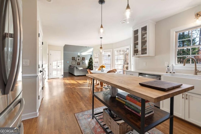 kitchen featuring white cabinets, pendant lighting, stainless steel appliances, and butcher block countertops