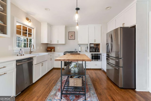 kitchen with pendant lighting, stainless steel appliances, white cabinetry, and sink