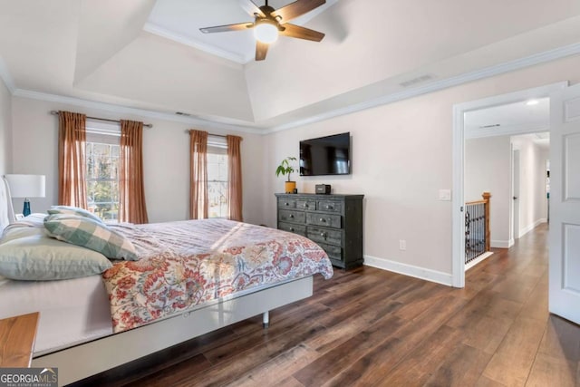 bedroom featuring ceiling fan, ornamental molding, dark wood-type flooring, and a tray ceiling