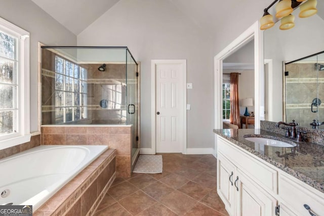 bathroom featuring shower with separate bathtub, vanity, vaulted ceiling, and a wealth of natural light