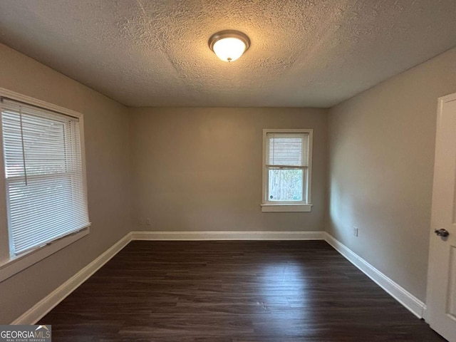 unfurnished room with dark hardwood / wood-style floors and a textured ceiling