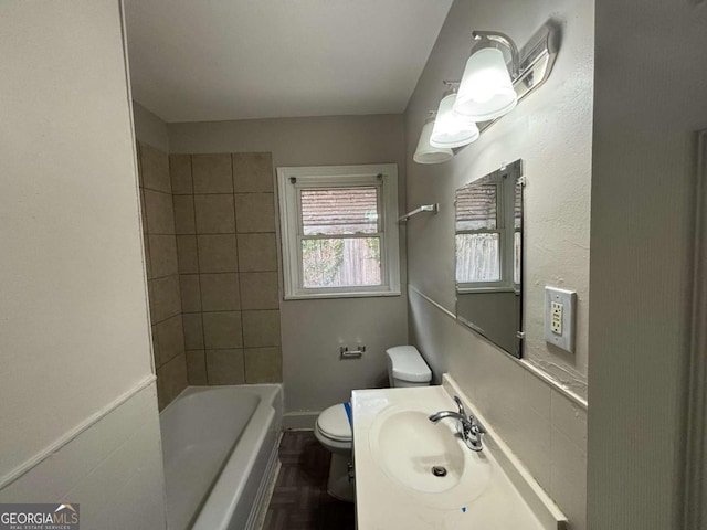 full bathroom with sink, tiled shower / bath, parquet flooring, and toilet