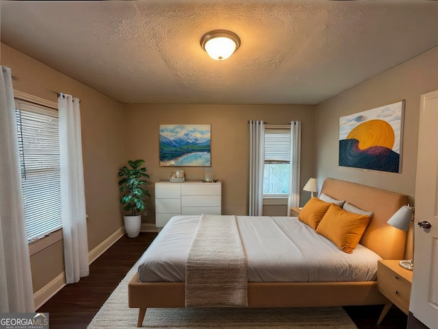 bedroom featuring dark wood-type flooring, multiple windows, and a textured ceiling