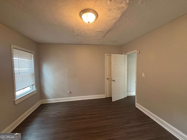 empty room with dark wood-type flooring and a textured ceiling