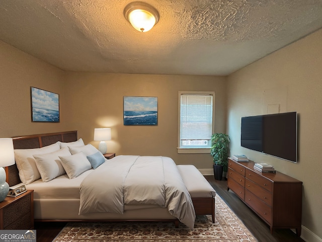 bedroom with dark hardwood / wood-style floors and a textured ceiling