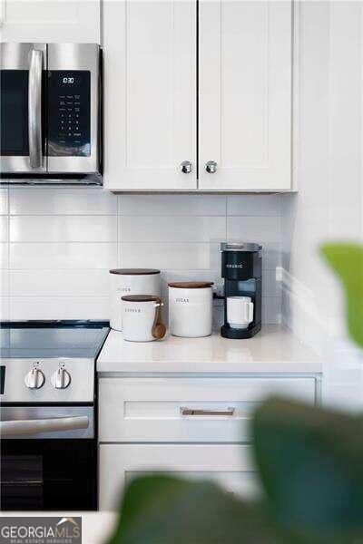 kitchen with white cabinets, range, and tasteful backsplash