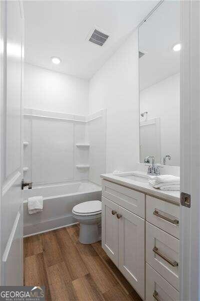 full bathroom featuring toilet, vanity, shower / bathtub combination, and hardwood / wood-style flooring