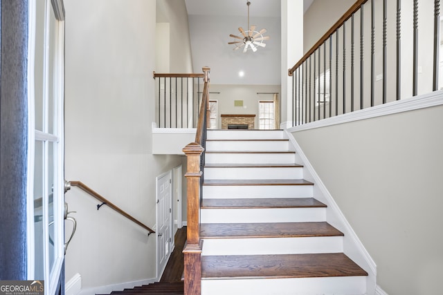 staircase with hardwood / wood-style flooring, ceiling fan, and a fireplace