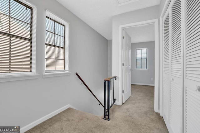 hallway with a healthy amount of sunlight and light colored carpet