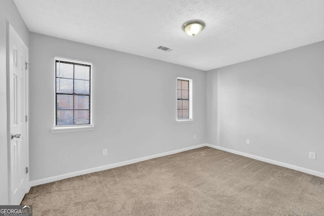 empty room featuring a textured ceiling and light colored carpet