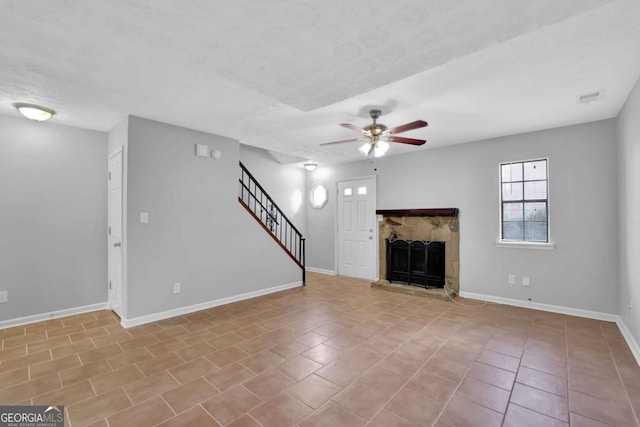 unfurnished living room featuring light tile patterned floors, a textured ceiling, a stone fireplace, and ceiling fan