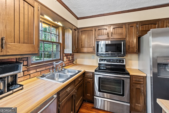 kitchen featuring sink, appliances with stainless steel finishes, backsplash, ornamental molding, and a textured ceiling