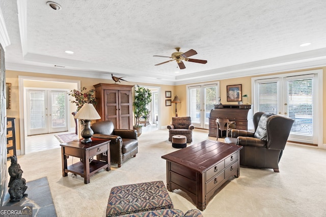 carpeted living room featuring crown molding, a tray ceiling, a textured ceiling, and french doors