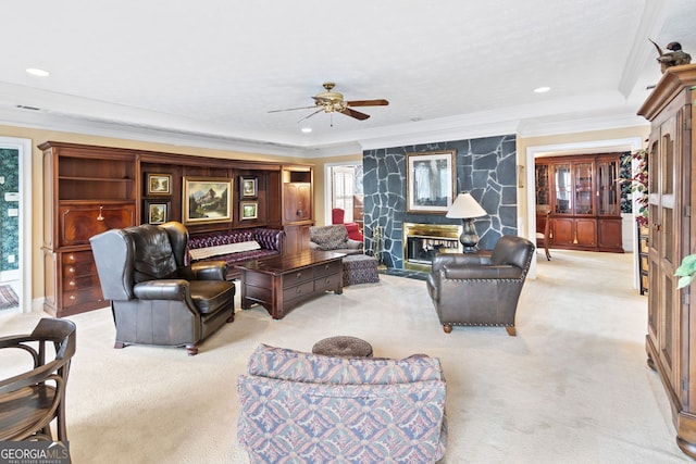 living room featuring ceiling fan, ornamental molding, a fireplace, and light carpet