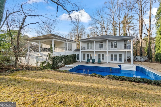 rear view of house featuring a patio area, french doors, a balcony, and a lawn