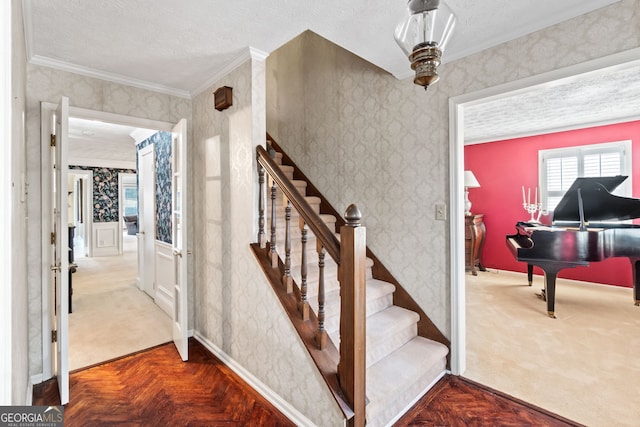 stairs with ornamental molding, carpet flooring, and a textured ceiling